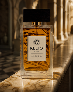 KLEIO Paris Silencio eau de parfum, amber bottle with black cap on a marble ledge in a sunlit classical colonnade.